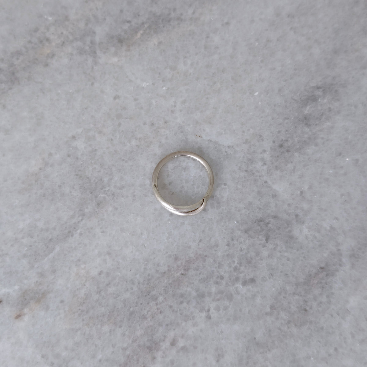 Side view of a Silver vine ring on a marble surface