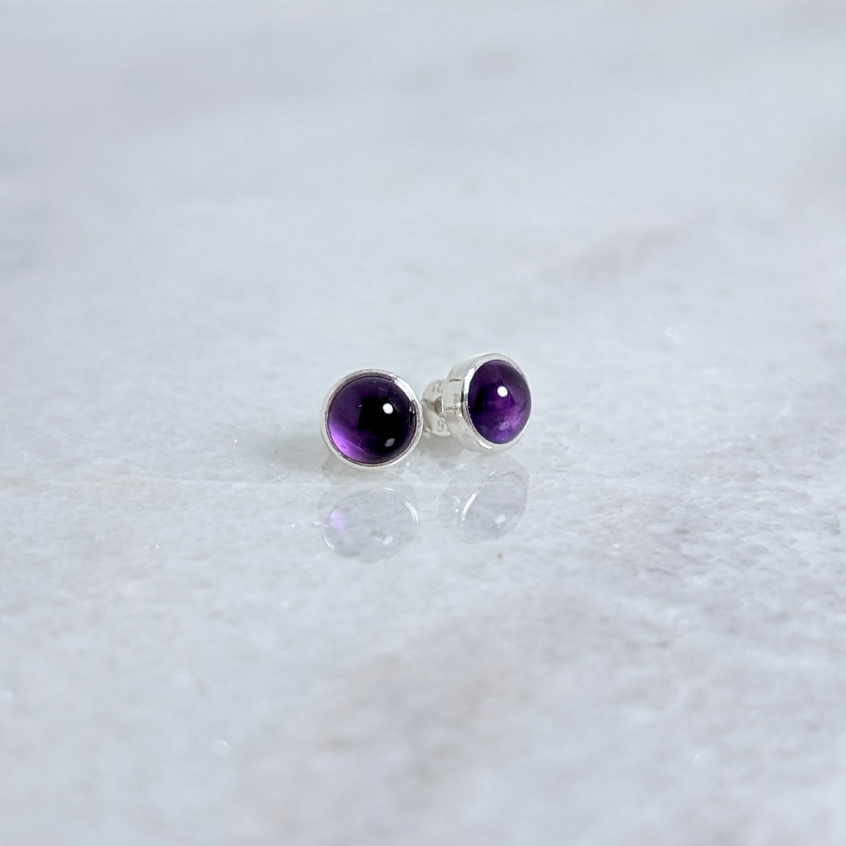 Amethyst studs on a white marble surface