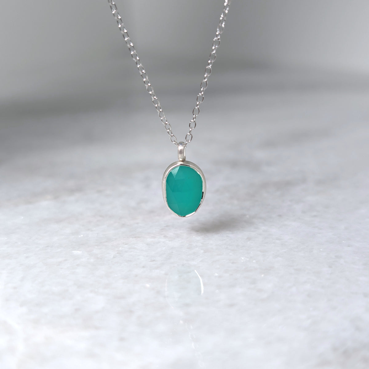 Teal pendant necklace on a white background
