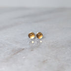 A pair of round citrine cabochons set in silver studs on a marble surface