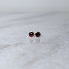 A pair of round garnet rose cut cabochons set in silver studs on a marble surface