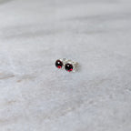A pair of round garnet rose cut cabochons set in silver studs on a marble surface