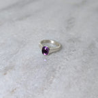 Silver ring with an amethyst center stone on a white marble background