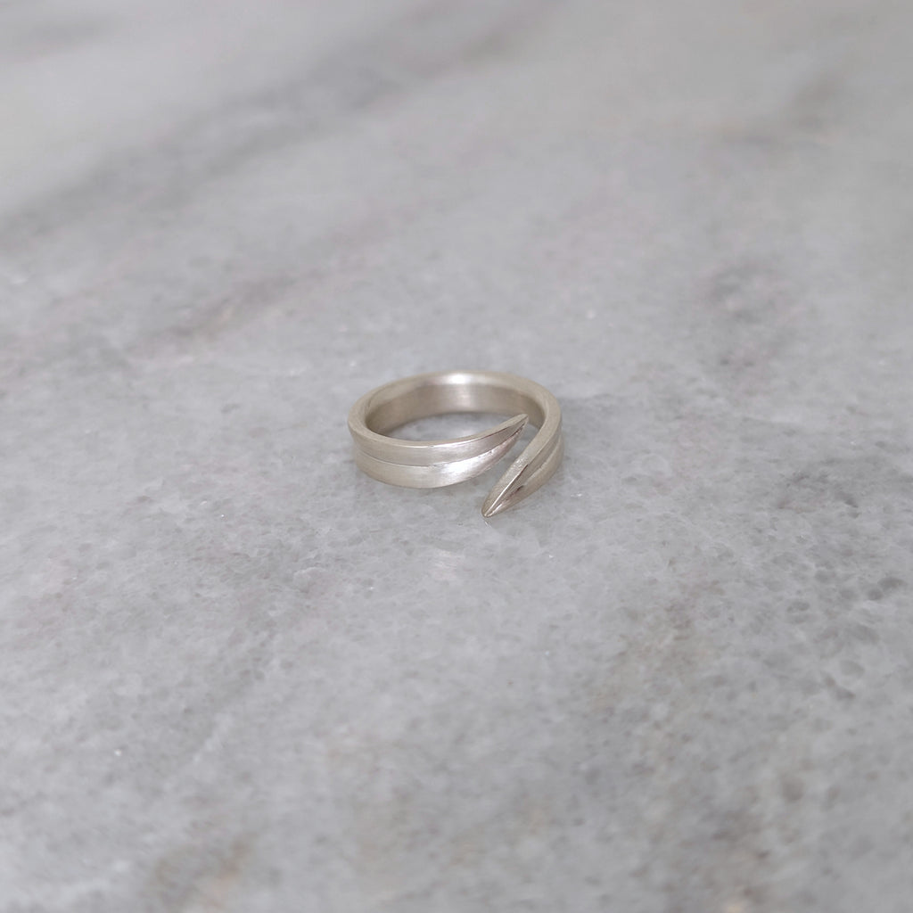 Angled view of a silver leaf blade ring on a marble surface