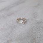 Angled view of a silver leaf blade ring on a marble surface