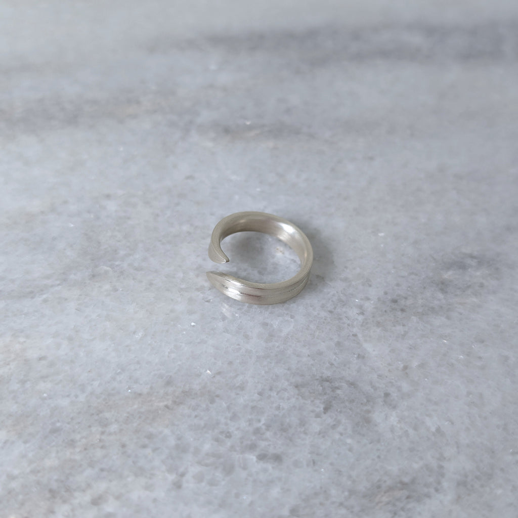Angled view of a silver leaf blade ring on a marble surface
