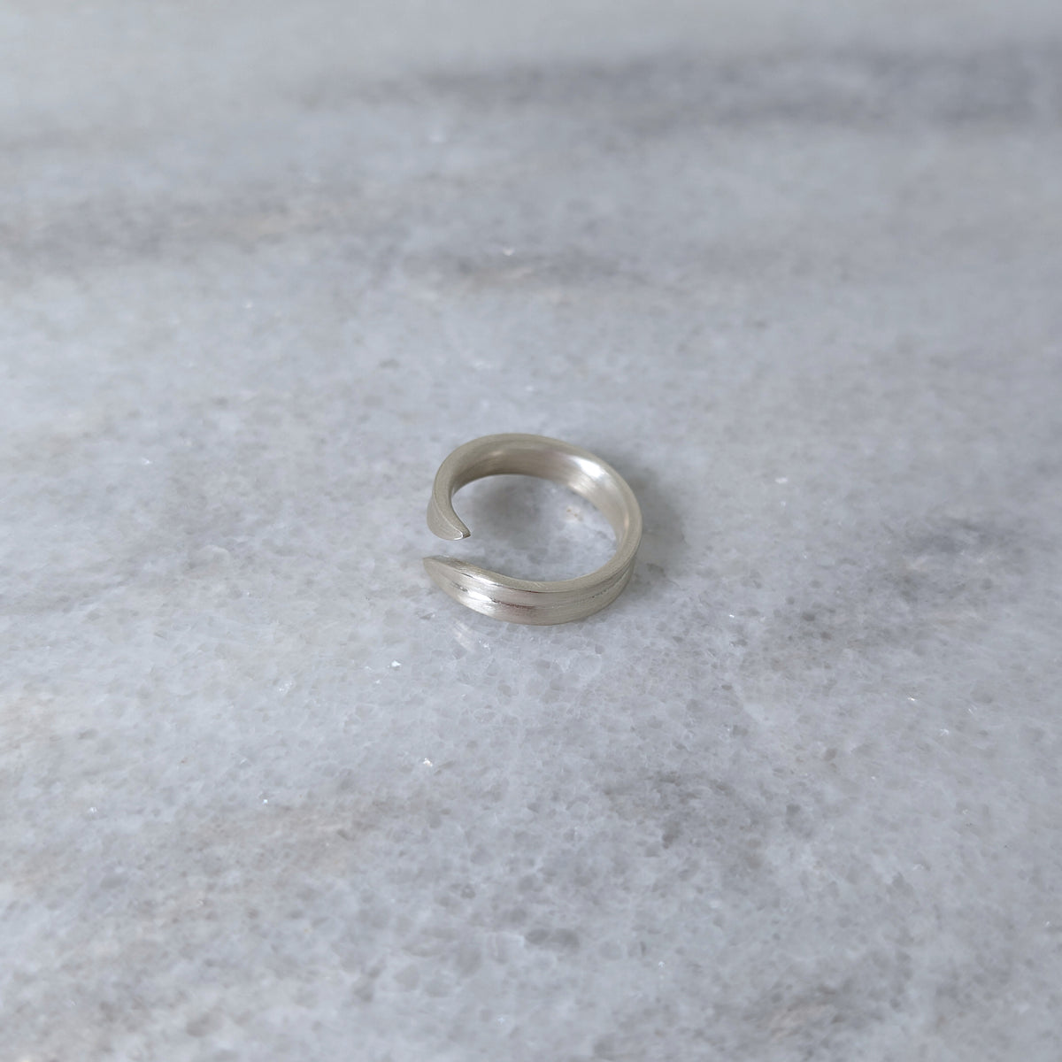 Angled view of a silver leaf blade ring on a marble surface