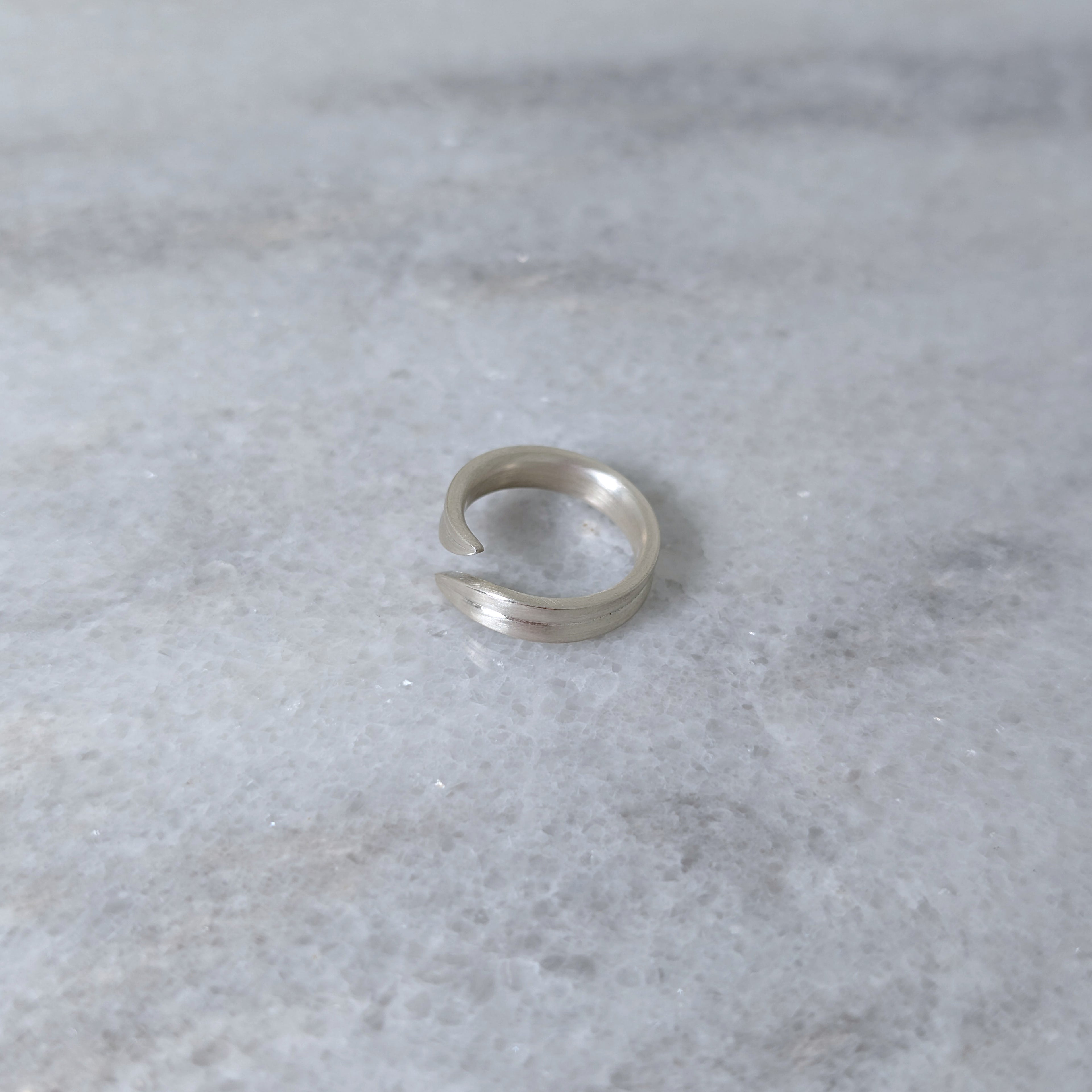 Angled view of a silver leaf blade ring on a marble surface