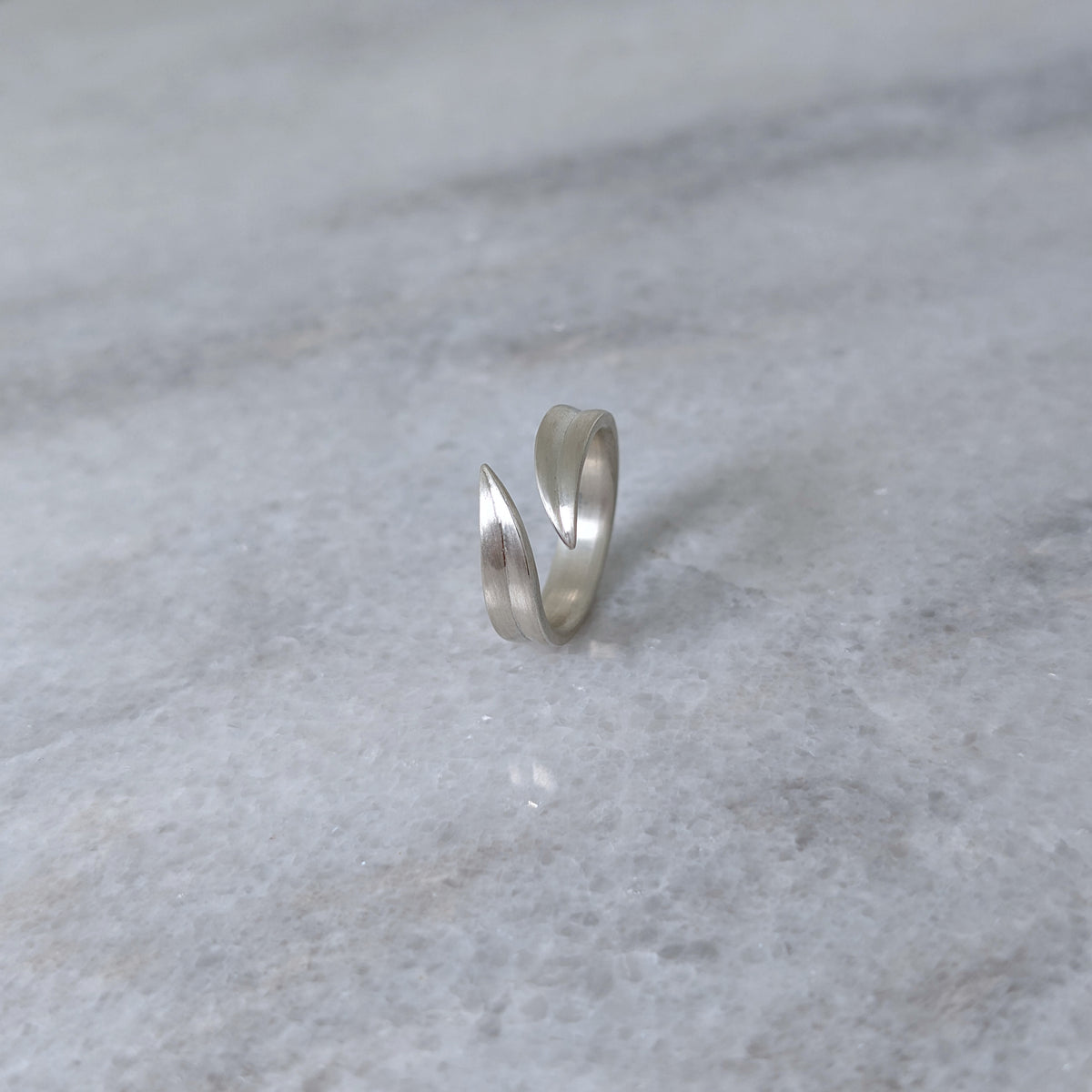 Angled view of a silver leaf blade ring on a marble surface