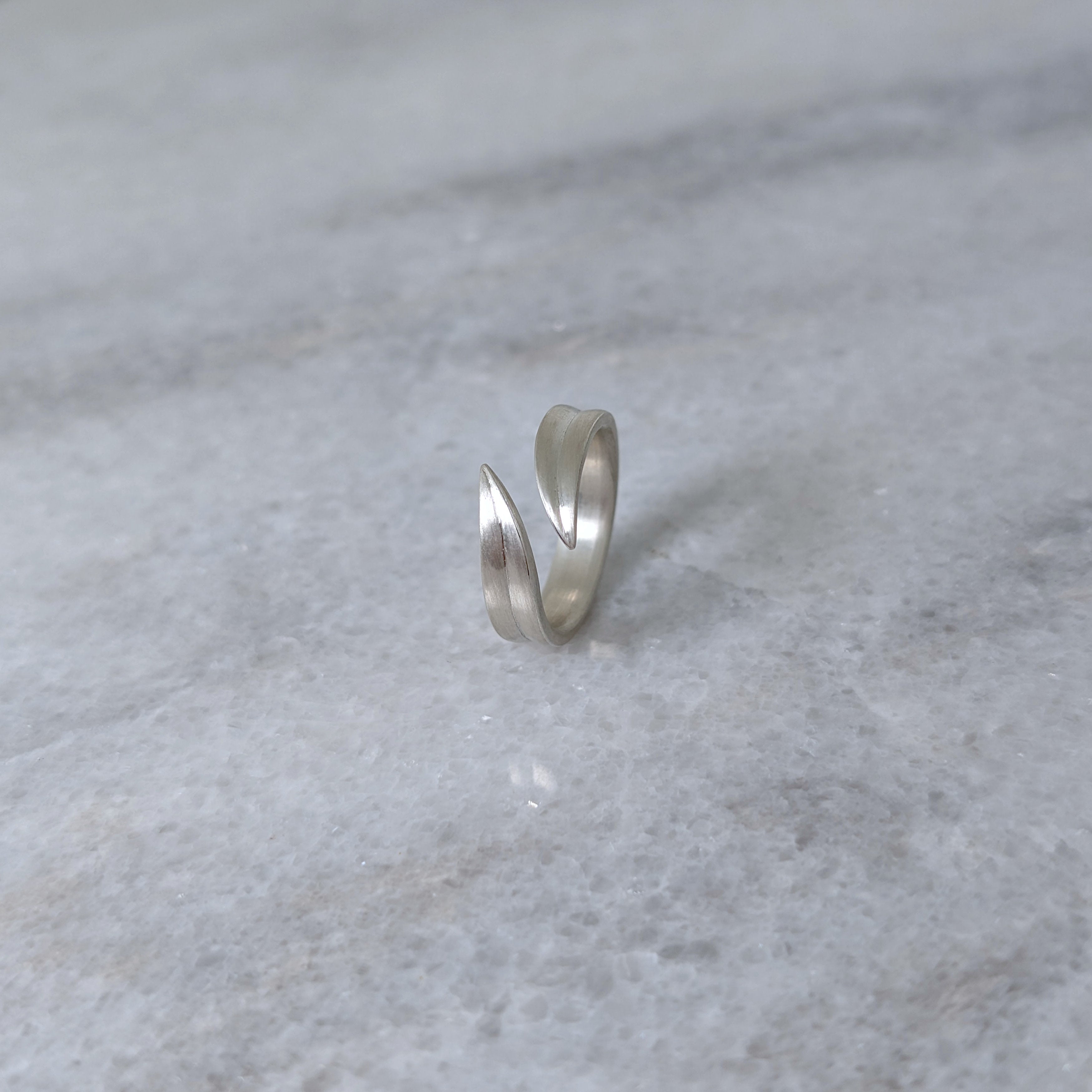 Angled view of a silver leaf blade ring on a marble surface