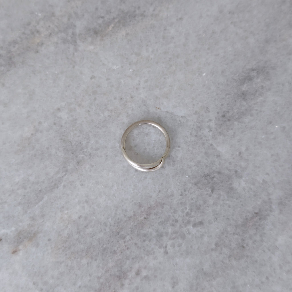 Side view of a Silver vine ring on a marble surface