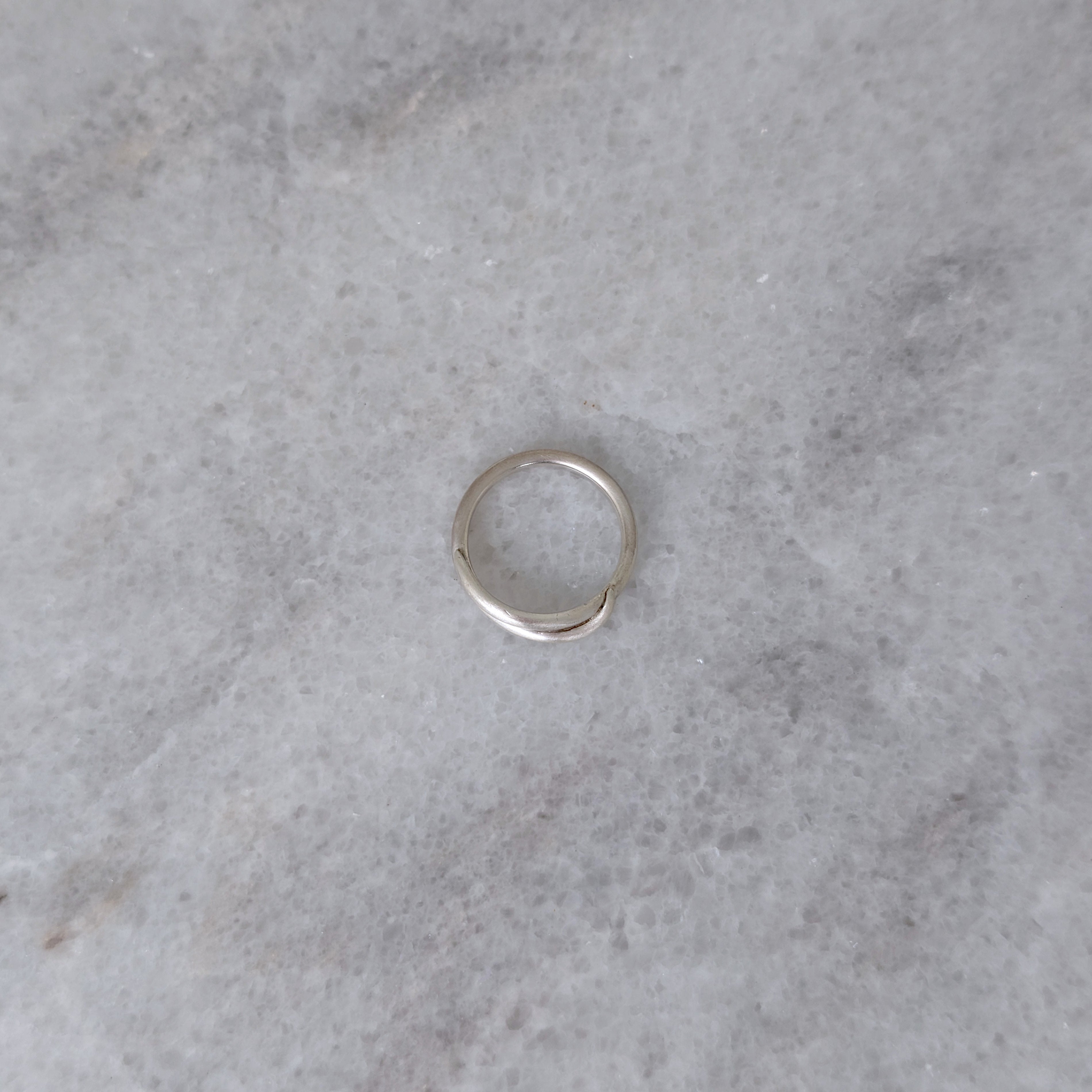 Side view of a Silver vine ring on a marble surface