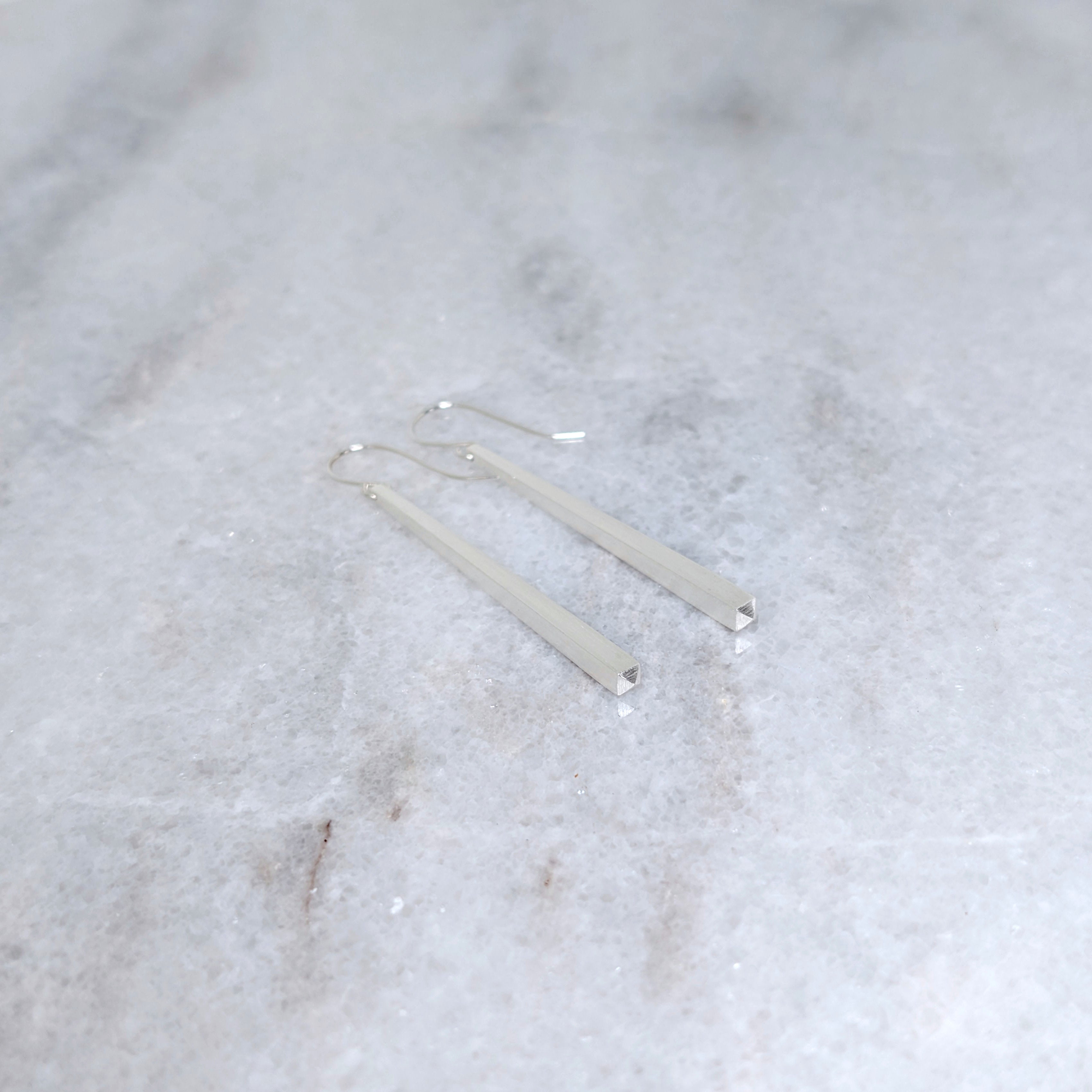 Silver tapered earrings on a marble surface