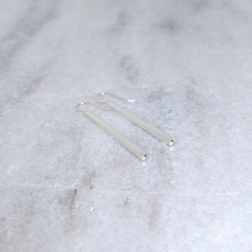 Silver tapered earrings on a marble surface